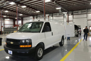 Utility rack installed on top of van with two workers inside workstation Utility rack installed on top of van with two workers inside workstation