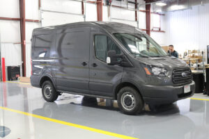 Custom van parked at workstation preparing to be upfitted by worker Custom van parked at workstation preparing to be upfitted by worker