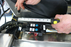 Worker measures wire harness layout inside emergency vehicle Worker measures wire harness layout inside emergency vehicle