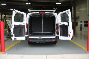 White commercial van with back doors open parked inside workstation White commercial van with back doors open parked inside workstation